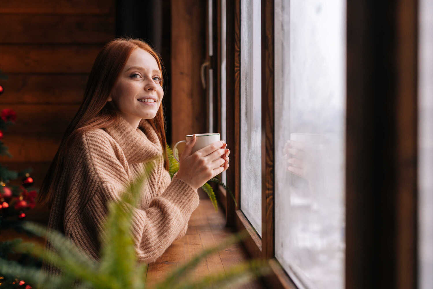 side-view-of-charming-smiling-young-red-haired-woman-with-cup-standing-by-window-at-home.-1290587665-6000x4000.jpeg